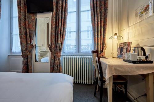 a hotel room with a bed and a table and a window at Hotel Saint Etienne in Caen