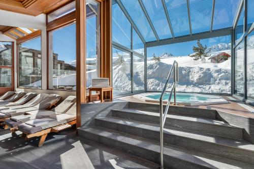 a glass house with a plunge pool with a view at Hotel Annapurna in Courchevel