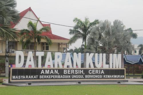 a large sign in front of a building with palm trees at Big Apple Hotel in Kulim