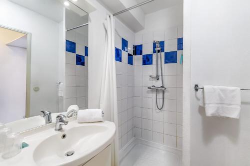 La salle de bains blanche est pourvue d'une douche et d'un lavabo. dans l'établissement Appart'City Classic Thonon Les Bains, à Thonon-les-Bains