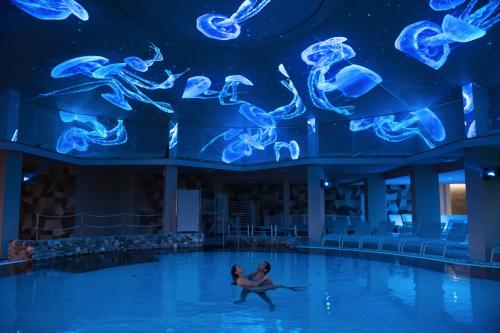 a man and a woman swimming in the pool at Plaza Hotel Abano Terme in Abano Terme