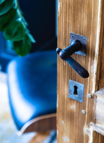 a black door handle on a wooden door with a chair at Kaai11 - Riverview Lofts & Suites in Antwerp