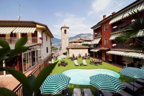 a courtyard with chairs and umbrellas and a clock tower at Albergo Casa Este in Brenzone sul Garda
