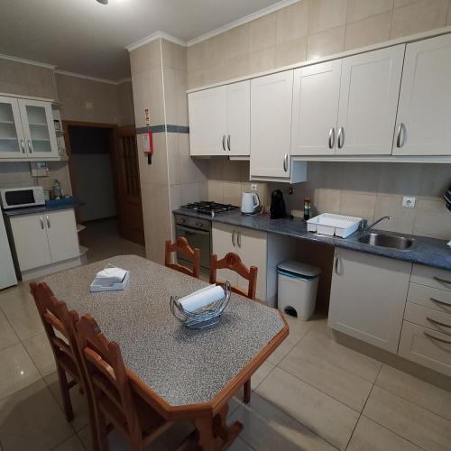 a kitchen with a table and chairs and white cabinets at Apartamento Solmar in Ponta Delgada