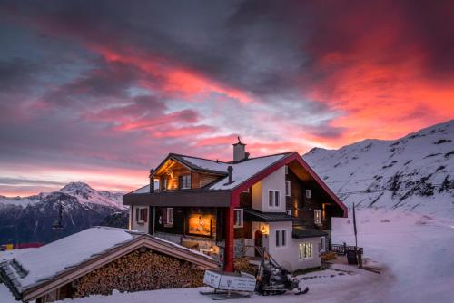 a house in the snow with a sunset at Hamilton Lodge & Spa in Belalp