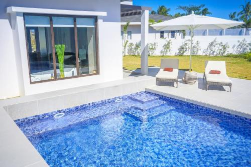 a villa with a swimming pool and two chairs at Kandaya Resort in Daanbantayan
