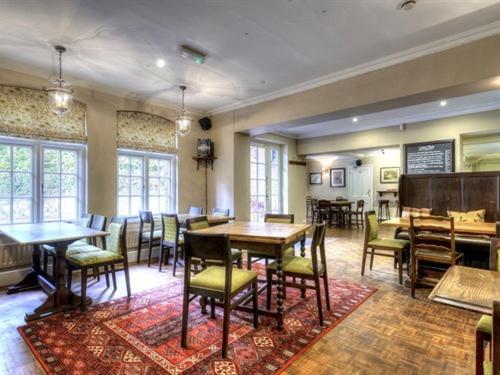 a dining room with tables and chairs and windows at The Talbot in Iwerne Minster