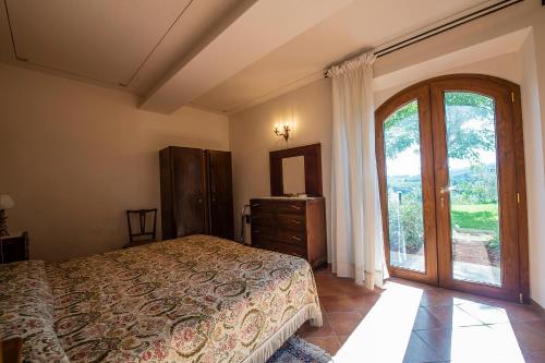 1 dormitorio con cama y ventana grande en Uliveta, en San Gimignano