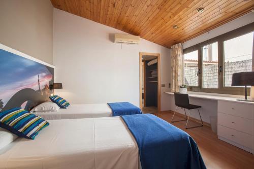 a bedroom with two beds and a desk with a chair at BCNGOTIC 50 in Barcelona