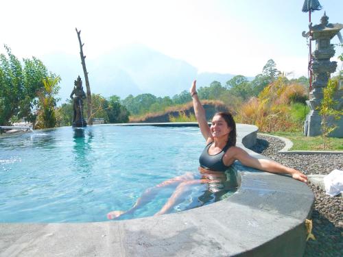 a woman is sitting in a swimming pool at Batur Pyramid Guesthouse in Kintamani