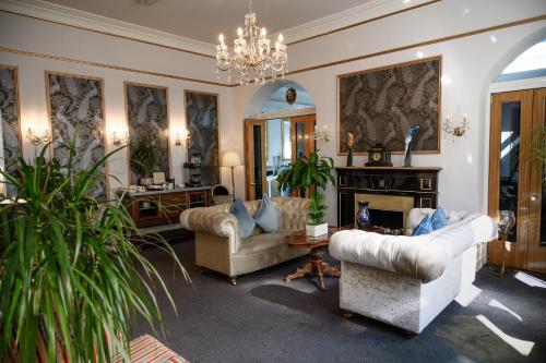 a living room with couches and a chandelier at Derby Manor in Bournemouth