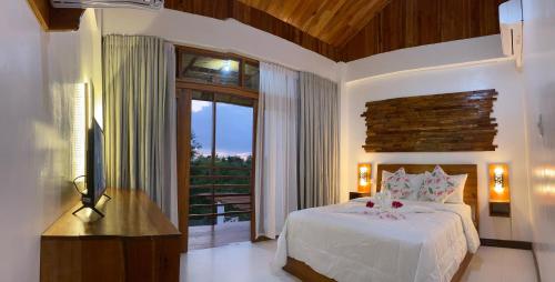 a bedroom with a white bed and a balcony at Ananda Resort in Panglao