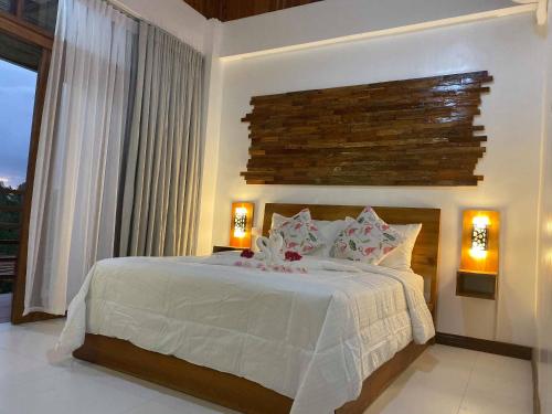 a bedroom with a white bed with two lamps and a window at Ananda Resort in Panglao