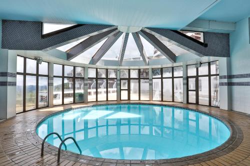 a large swimming pool in a building with windows at Hotel Home Green Home in Campos do Jordão