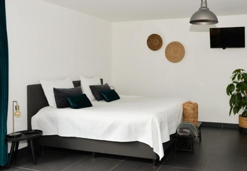 1 dormitorio con cama blanca y almohadas negras en B & B Meet the Dutch en Ridderkerk