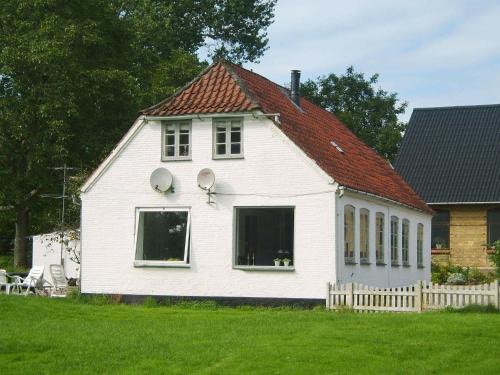 a white house with two windows and a red roof at 4 person holiday home in Broager in Broager