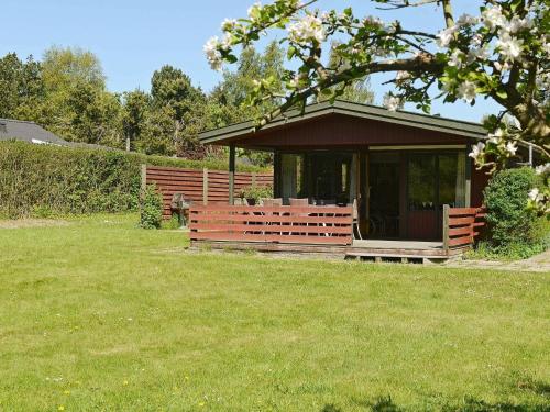 una cabaña en un campo de hierba con un árbol en 6 person holiday home in Pr st en Togeholt