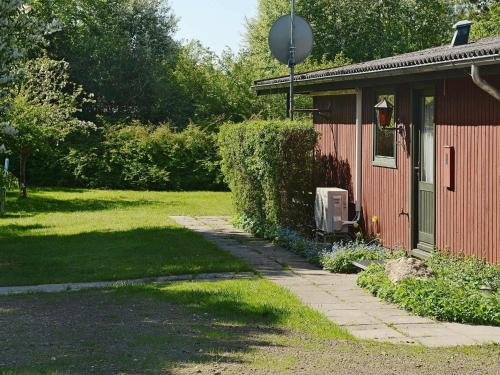 una casa roja con una pasarela junto a un patio en 6 person holiday home in Pr st en Togeholt