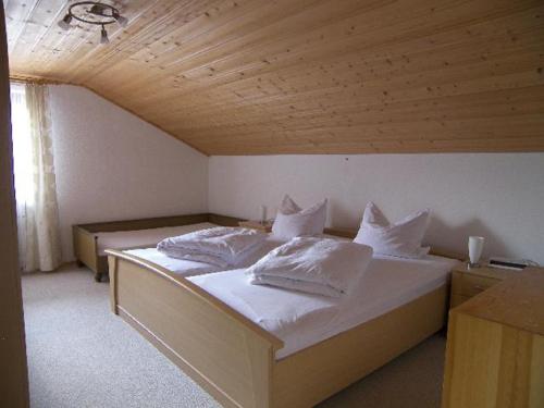 Schlafzimmer mit einem Bett mit weißer Bettwäsche und Kissen in der Unterkunft Ferienhaus Sonja in Lindberg