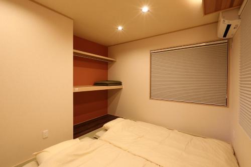 a small bedroom with a bed and a window at ゲストハウス奈良庵 Nara An in Nara