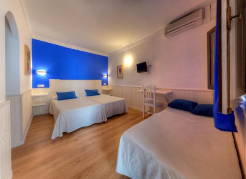 a hotel room with two beds and a blue wall at Hostal Alhambra in Zahora