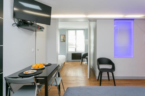 un salon avec une table et des chaises dans une pièce dans l'établissement Sourdiere Louvre Vendome with AC, à Paris