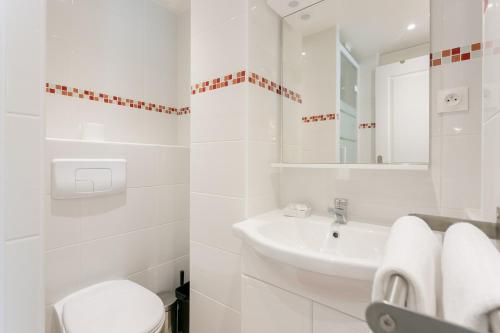 une salle de bain blanche avec un lavabo et des toilettes dans l'établissement Sourdiere Louvre Vendome with AC, à Paris