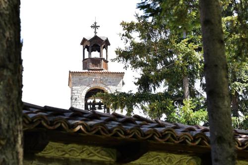 a church steeple with a cross on top of a roof at Hotel Alpin - 91 Bansko in Bansko