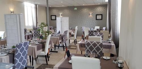 Logis Hotel Restaurant Le Vedaquais في Vaas: غرفة طعام مع طاولات وكراسي بيضاء وحارق طاولات
