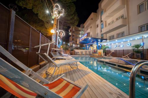 a swimming pool with lounge chairs next to a building at Hotel Corallo Rimini in Rimini
