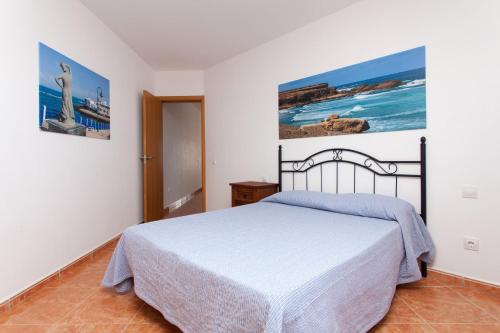 a bedroom with a bed and paintings on the wall at TAO El Cotillo in El Cotillo