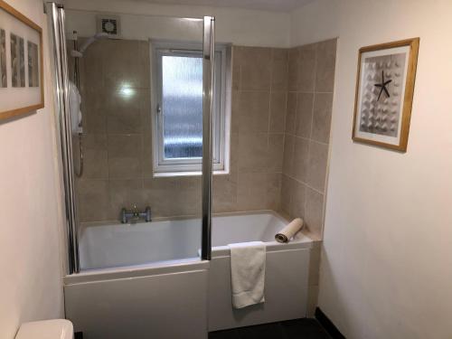 uma casa de banho com uma banheira e um chuveiro com uma janela em Last Yan Cottage em Ambleside