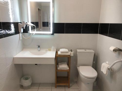 a bathroom with a sink and a toilet and a mirror at Hôtel Restaurant Les Falaises in Bouziès