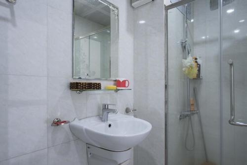 Un baño blanco con lavabo y ducha en Homestay sea view Newlife Halong., en Ha Long