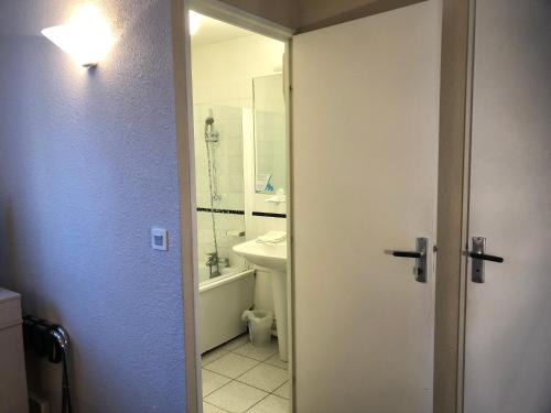 a bathroom with a toilet and a sink and a door at Hôtel Restaurant Les Falaises in Bouziès