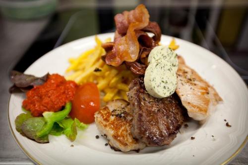 a white plate of food with meat and vegetables at Hotel Schäfflerwirt in Aschheim