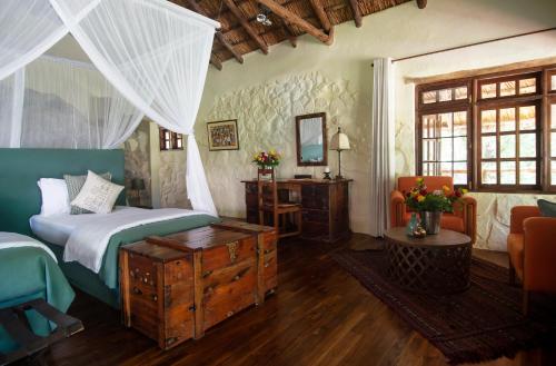 a bedroom with a bed and a table and a mirror at Rivertrees Country Inn in Usa River