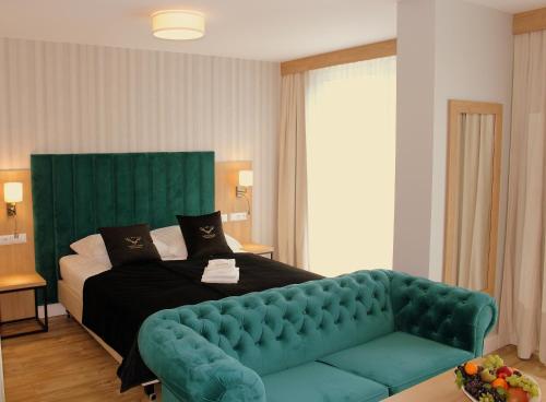 een slaapkamer met een bed met een groene fluwelen bank bij Hotel Echo in Cedzyna