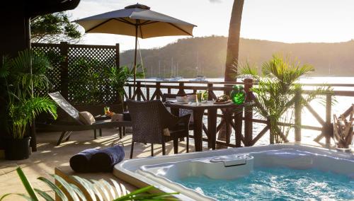 a hot tub on a patio with a table and an umbrella at Secret Harbour Boutique Hotel and Marina in Lance aux Épines