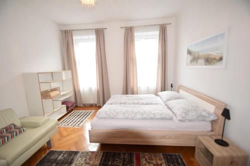 ein Schlafzimmer mit einem Bett, einem Sofa und Fenstern in der Unterkunft Apartment Villa Penzing in Wien