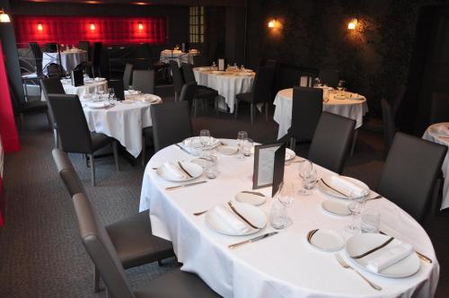 une salle à manger avec des tables et des chaises blanches et des assiettes blanches dans l'établissement Logis Hôtel A la Bonne Auberge, à Laval