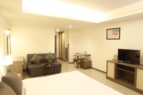 a living room with a couch and a television at Lee Garden Bangkok in Bangkok