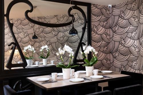 a table with white flowers on it in a restaurant at Grand Hotel des Balcons in Paris