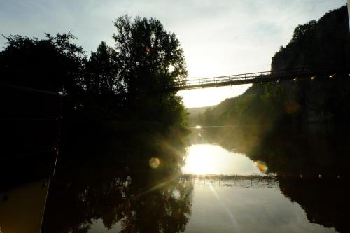 a bridge over a river with the sun reflecting on the water at Hôtel Restaurant Les Falaises in Bouziès