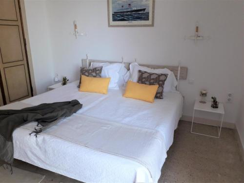 a bedroom with a large white bed with yellow pillows at Villa Transatlantique en première ligne de mer dite Villa Esmeralda in Llafranc