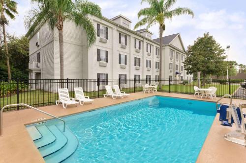 a pool in front of a building with palm trees at Baymont by Wyndham Ormond Beach in Ormond Beach
