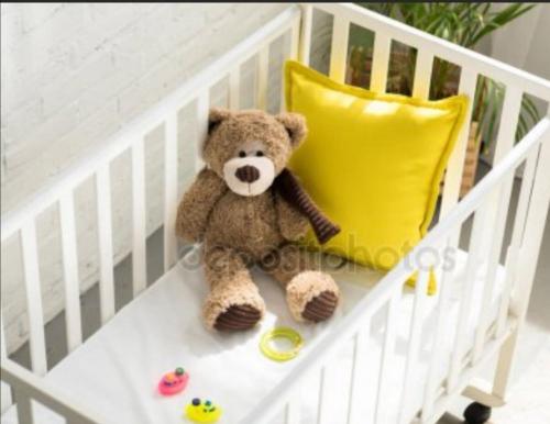 a teddy bear sitting in a crib with a yellow pillow at Family Apartment City Center Baden-Baden in Baden-Baden