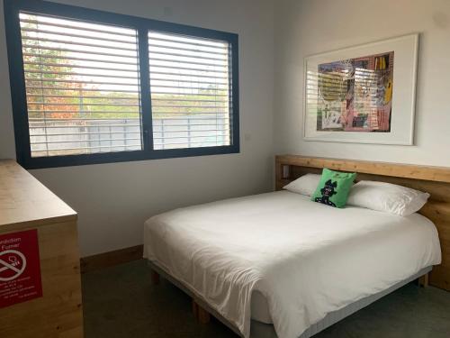 a bedroom with a white bed and two windows at Le B Complexe Hôtel in Lozanne