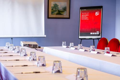 a conference room with tables and chairs and a screen at North Stafford Hotel in Stoke on Trent