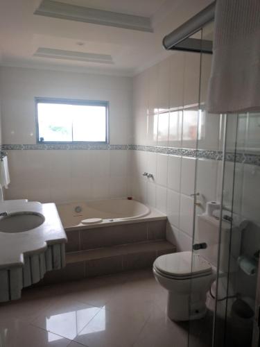 a bathroom with a tub and a toilet and a sink at Hotel Pousada Laje de Itauna in Saquarema